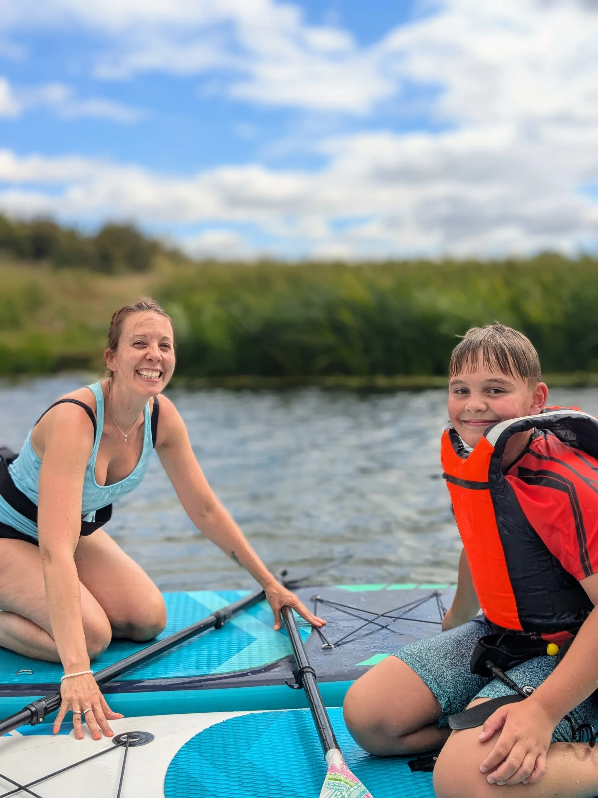 Mother and son kneeling on paddleboards
